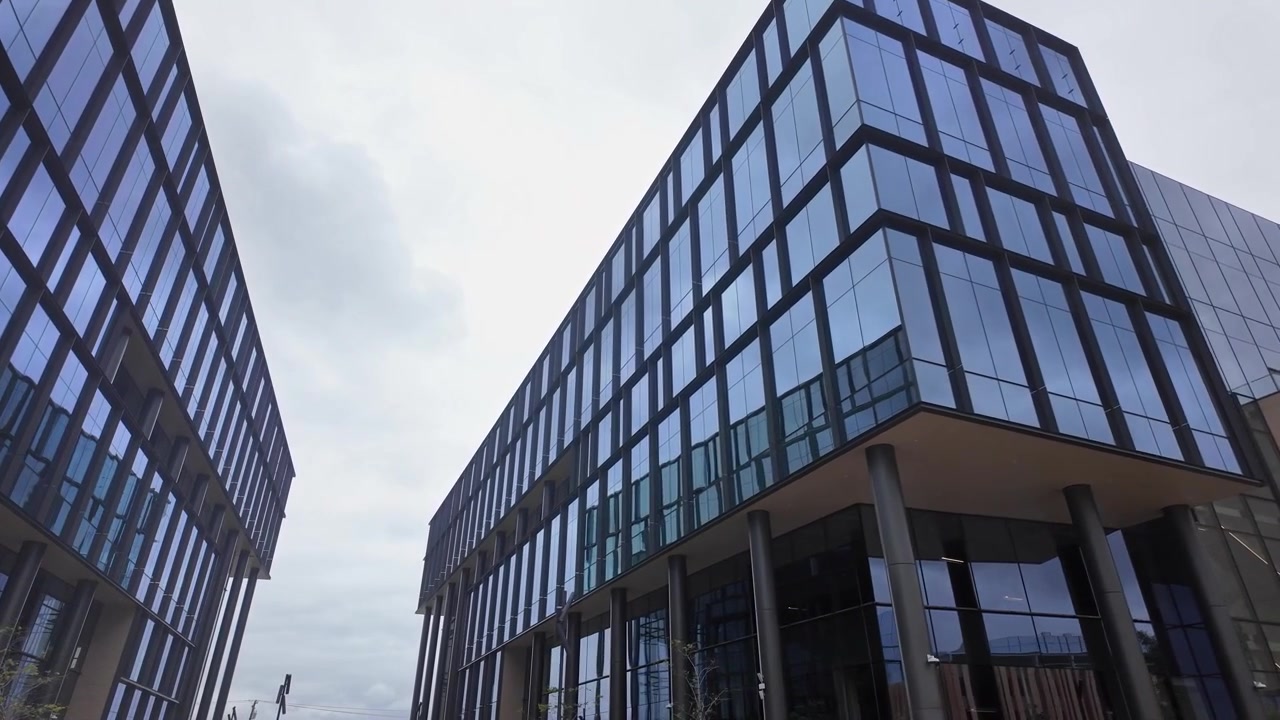 Perspectiva de ángulo bajo caminando hacia un moderno laboratorio médico con fachada de vidrio y edificio de oficinas corporativas en el sur de San Francisco, California, mostrando su diseño arquitectónico futurista