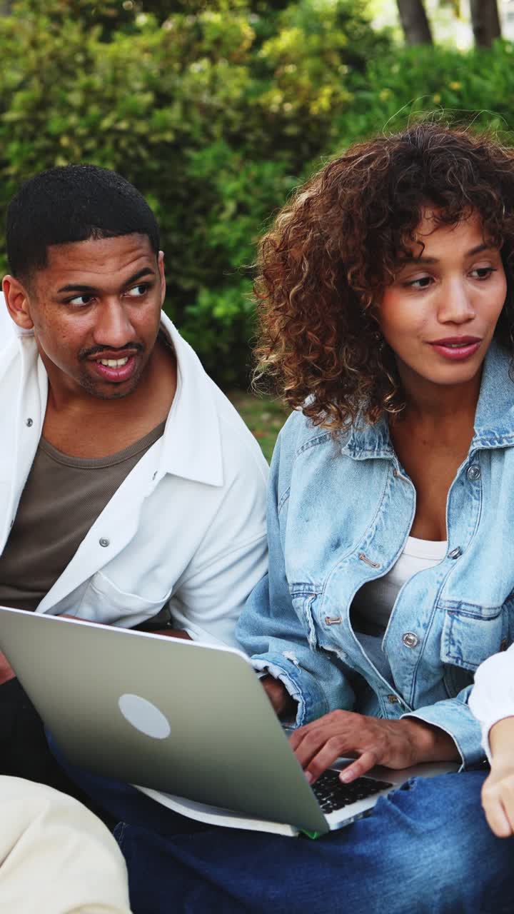Giovani uomo e donna che collaborano al laptop all'aperto