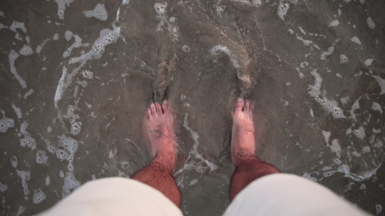 Satisfying view of feets in the sand caressed by a wave