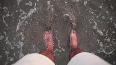 satisfying view of feets in the sand caressed by a wave
