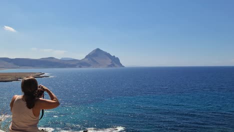 Woman-take-panoramic-picture-with-camera-of-Baia-Santa-Margherita-Sicilian-beautiful-coast-of-Sicily-in-Italy