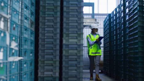 female storehouse employee inspecting blue supply crates checking delivery