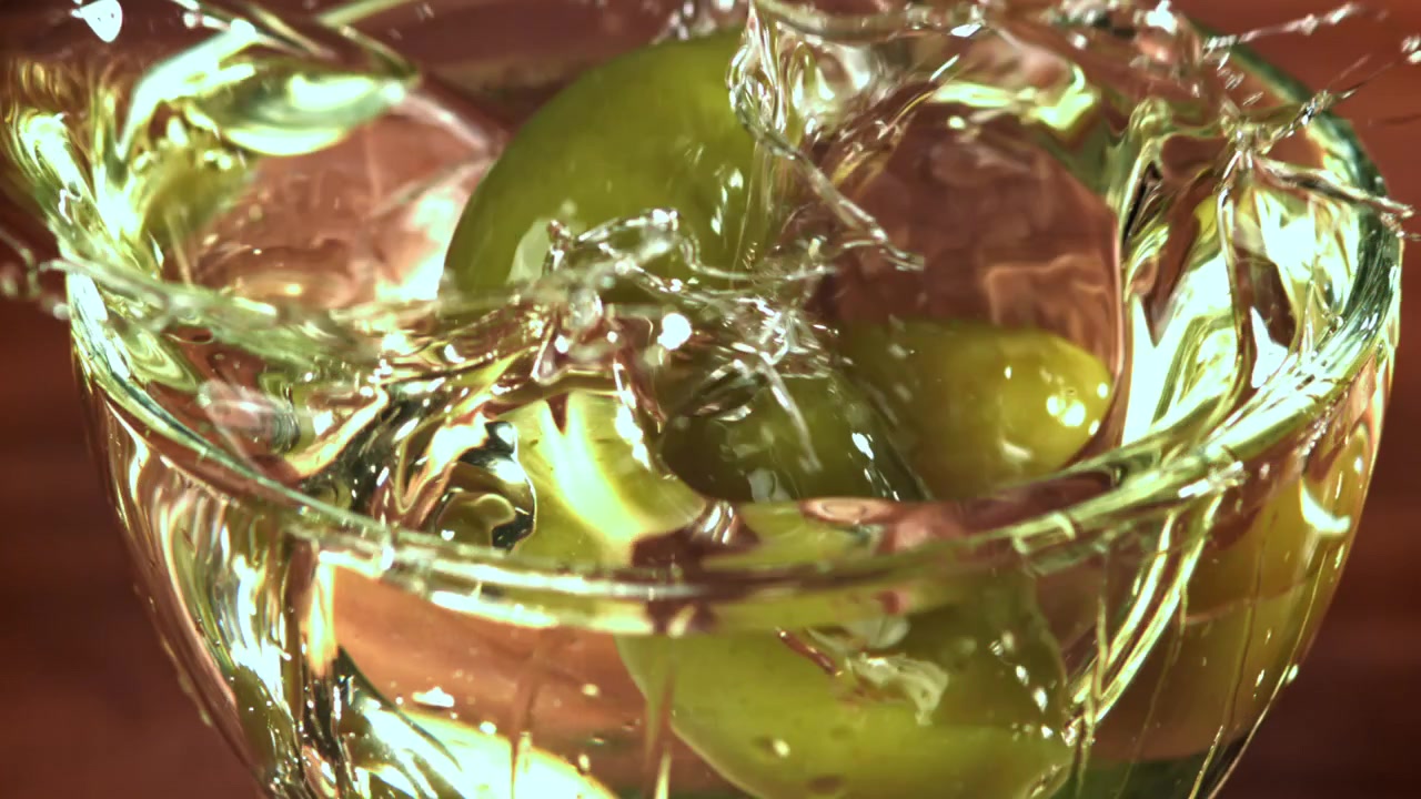 Cocktail Martini con olive verdi che schizzano al rallentatore