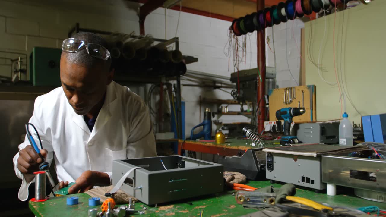 Male worker using soldering iron in glass factory 4k