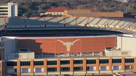 a zoomed-in drone shot at sunset panning right and revealing the longhorns logo on the empty darrell k royal texas memorial stadium at the university of texas (ut) in austin