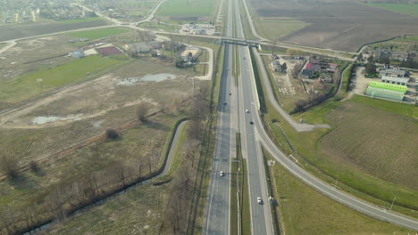 aerial backwards shot of driving cars on asphalt highway and bridges in poland