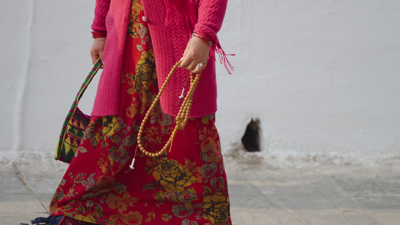 Devotees and Kora practitioners carrying malas and beads arrive at Boudhanath Temple, Kathmandu, Nepal, to perform their daily ritual of prayer and meditation in peace and devotion