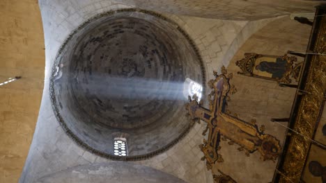 view looking up at the light beaming through windows in a church chapel in cyprus with an ornate cross in the foreground