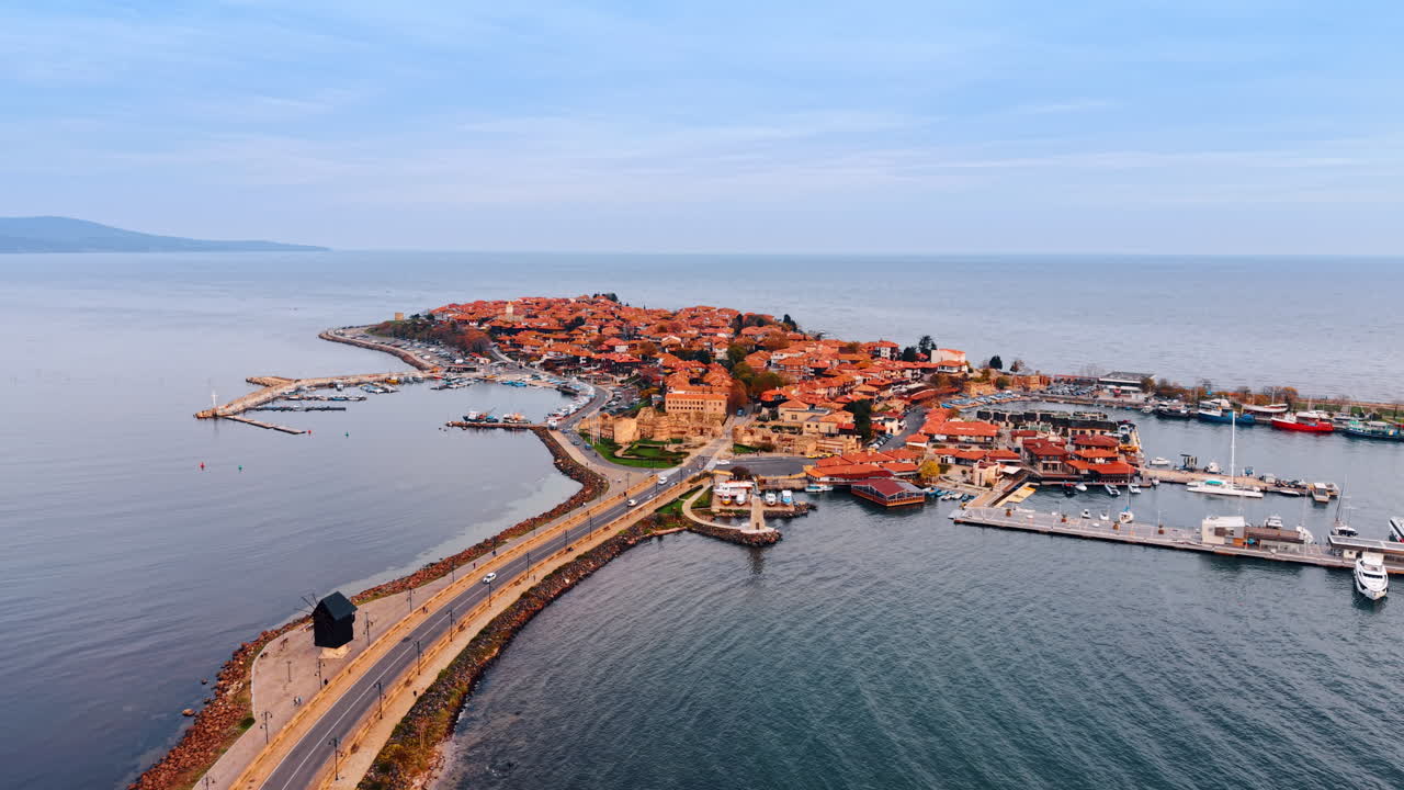 Bilar kör på vägen som går längs dammen och förbinder landbitarna i havslandskapet. Flygperspektiv över bostads- och semesterområdet Nessebar, Bulgarien.