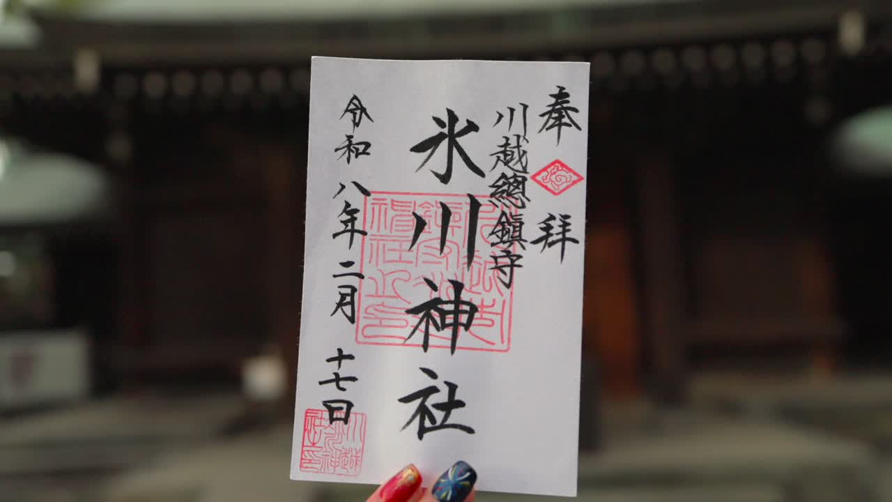 Frau hält einen traditionellen japanischen Goshuin-Stempel mit einem Tempel im unscharfen Hintergrund, der kulturelle Erkundung und Spiritualität symbolisiert