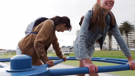 sideview of a caucasian and a mixed race girl on a merry-go-round looking at camera