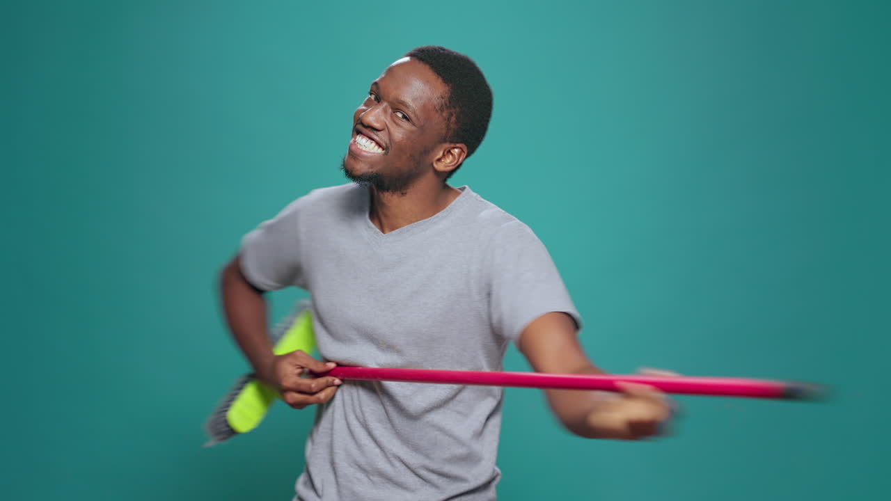 Portrait of foolish carefree singer playing guitar on broom