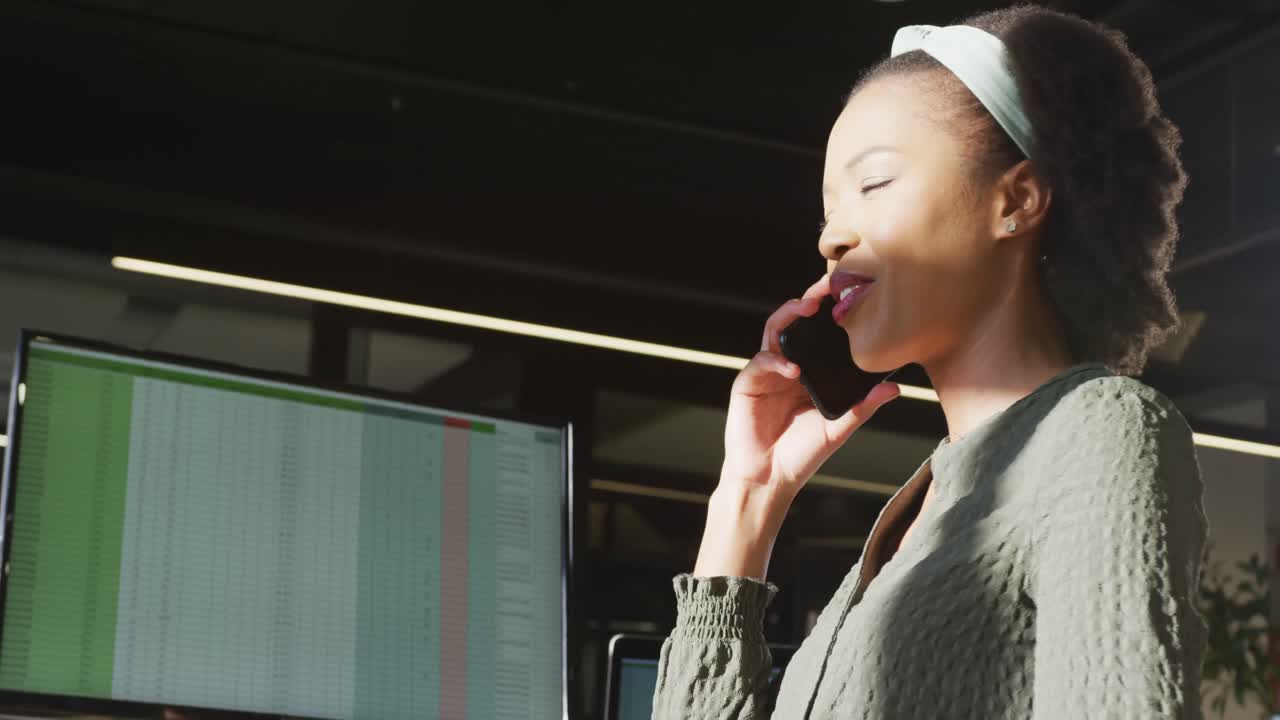 African american businesswoman sitting at table and using smartphone at office