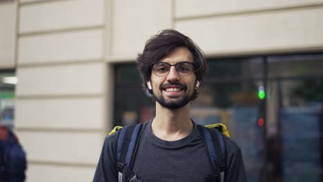 portrait of cheerful young male of food delivery service with large thermal backpack