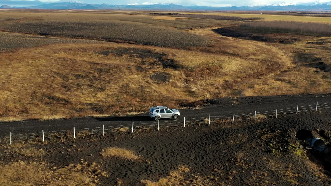 Vista laterale di un'auto che attraversa un paesaggio rurale giallo in Islanda