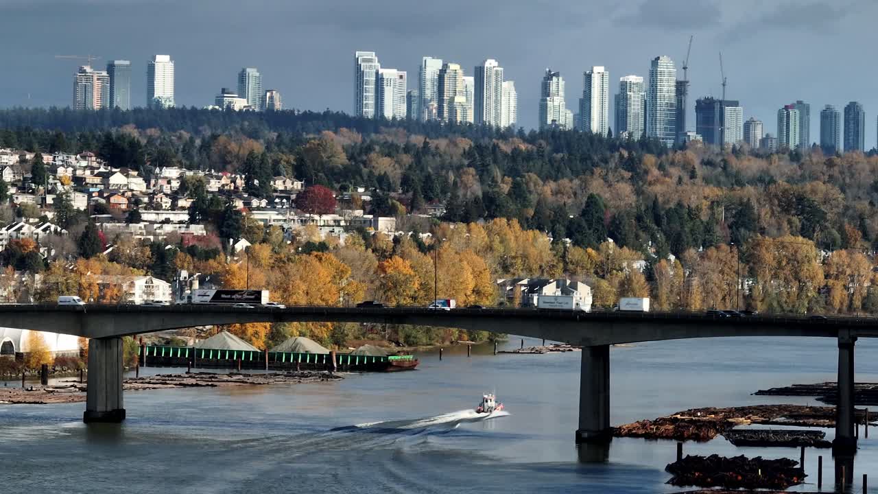 Imbarcazione di risposta alle fuoriuscite che passa sotto il ponte di Cambie sul False Creek. Skyline del centro di Vancouver e fogliame autunnale sullo sfondo. Ripresa laterale con drone