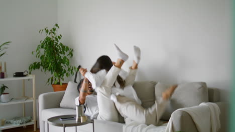 laughing family fooling around cozy home. smiling man holding wife playing