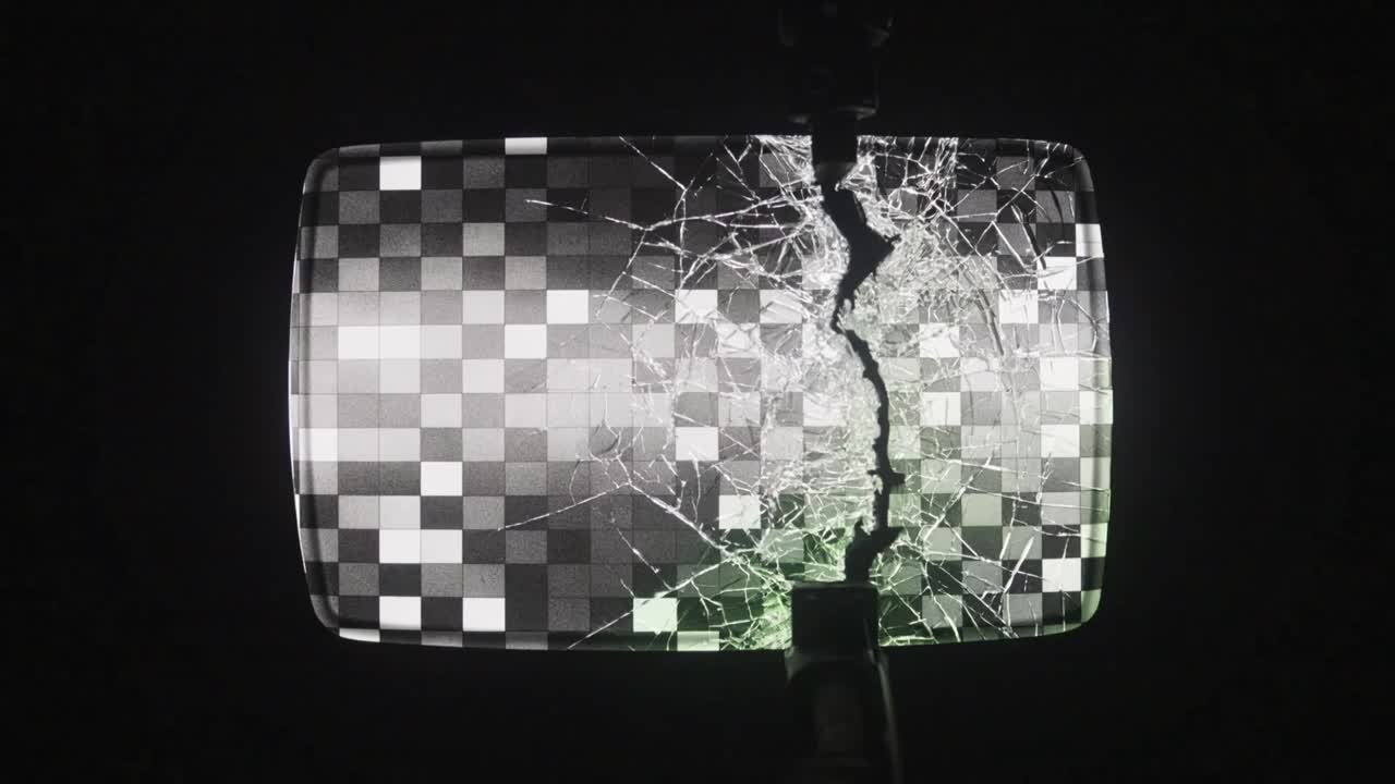 Cracking rectangular display showing gray checkerboard in dark lab, impactor contacting screen