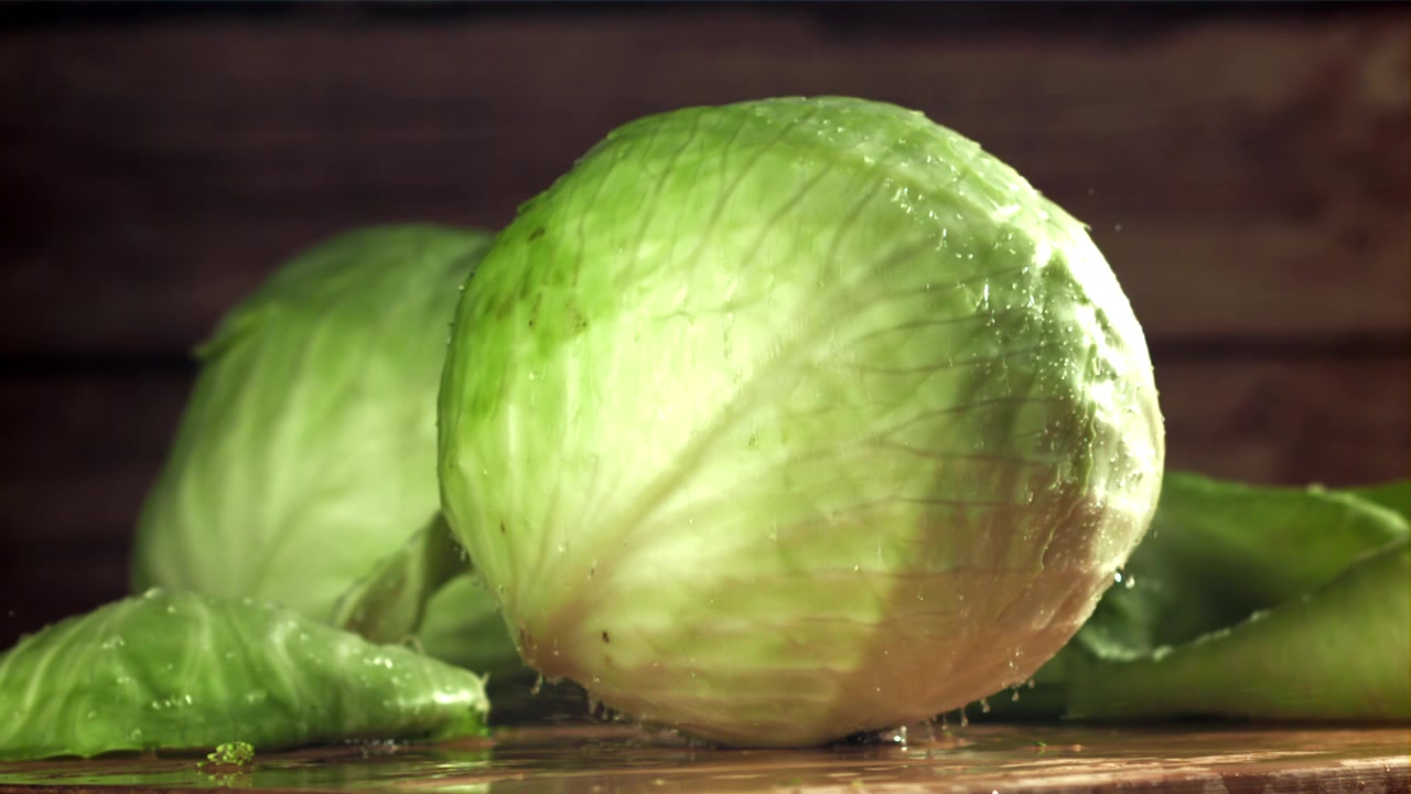 Lattuga iceberg fresca che cade al rallentatore con schizzi d'acqua