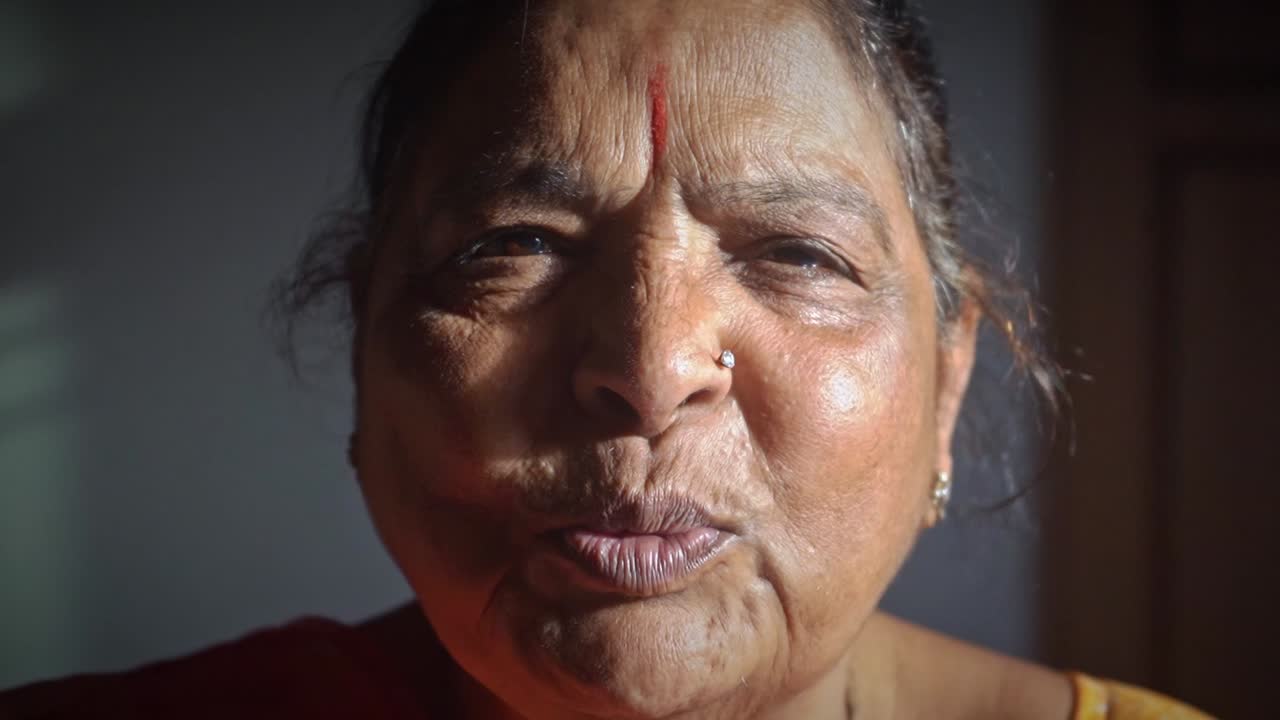 un retrato de una anciana frente a la cámara hablando en su idioma nativo en agra, india - primer plano