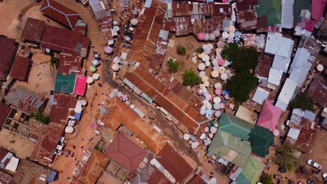 Top down aerial of a large market place in Karshi, Nigeria. The drone spins while people roam over the dirt roads in the shanty town