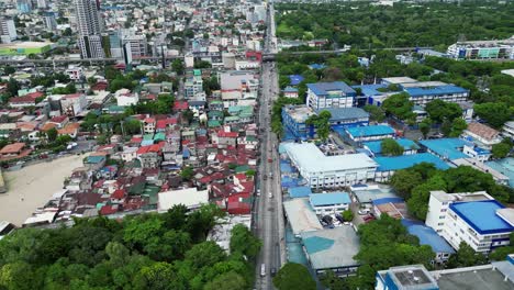 aerial forward shot of bustling highway with buildings and homes in middle of west crame, san juan city, philippines