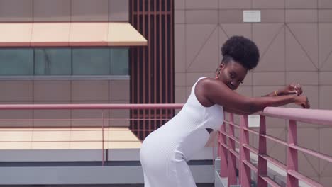 a young black girl wearing a white dress on a city rooftop