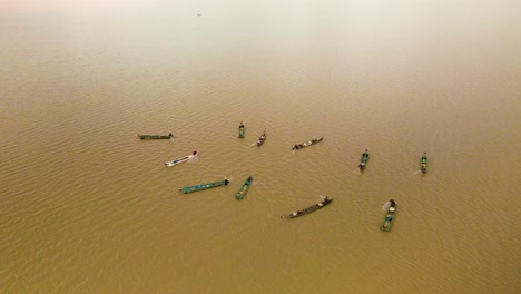 multiple fishermen in bright colorful boars working as a team gathering their fishing nets