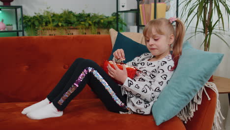 Niña-Sorprendida-Viendo-Un-Programa-De-Televisión-De-Vídeo-Cómico-O-Contenido-De-Una-Película-En-La-Televisión,-Comiendo-Palomitas-De-Maíz