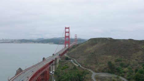 Wide-drone-shot-of-cars-driving-onto-San-Francisco's-Golden-Gate-Bridge-on-an-overcast-day