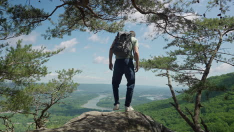 hiker climbs to top of a mountain overlooking beautiful view with river and green hills