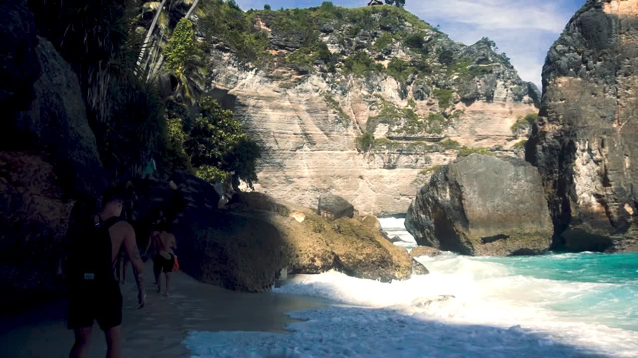 toma pov de turistas caminando en una playa rocosa de arena blanca durante un día soleado en bali