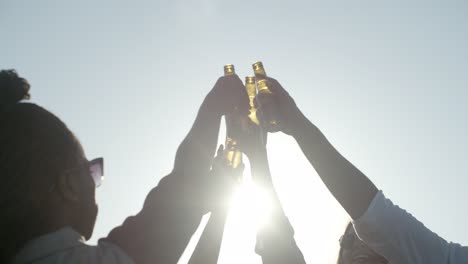 Gente-Feliz-Animando-Con-Botellas-De-Cerveza-Contra-El-Atardecer.