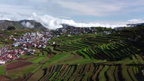 Scenic-drone-shot-of-Poombarai-village-on-Palani-hills-with-clouds-approaching-the-valley,-Terrace-farming-in-mountains,-Tamil-Nadu,-India