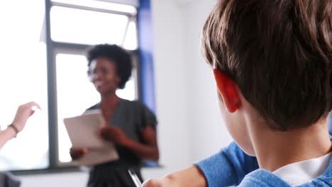 Pull-Focus-Shot-Of-Female-High-School-Tutor-Asking-Pupils-Sitting-Around-Table-Question-To-Which-They-Raise-Their-Hands