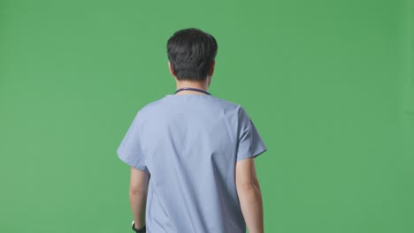 back view of asian male doctor with stethoscope walking on green screen background in the hospital