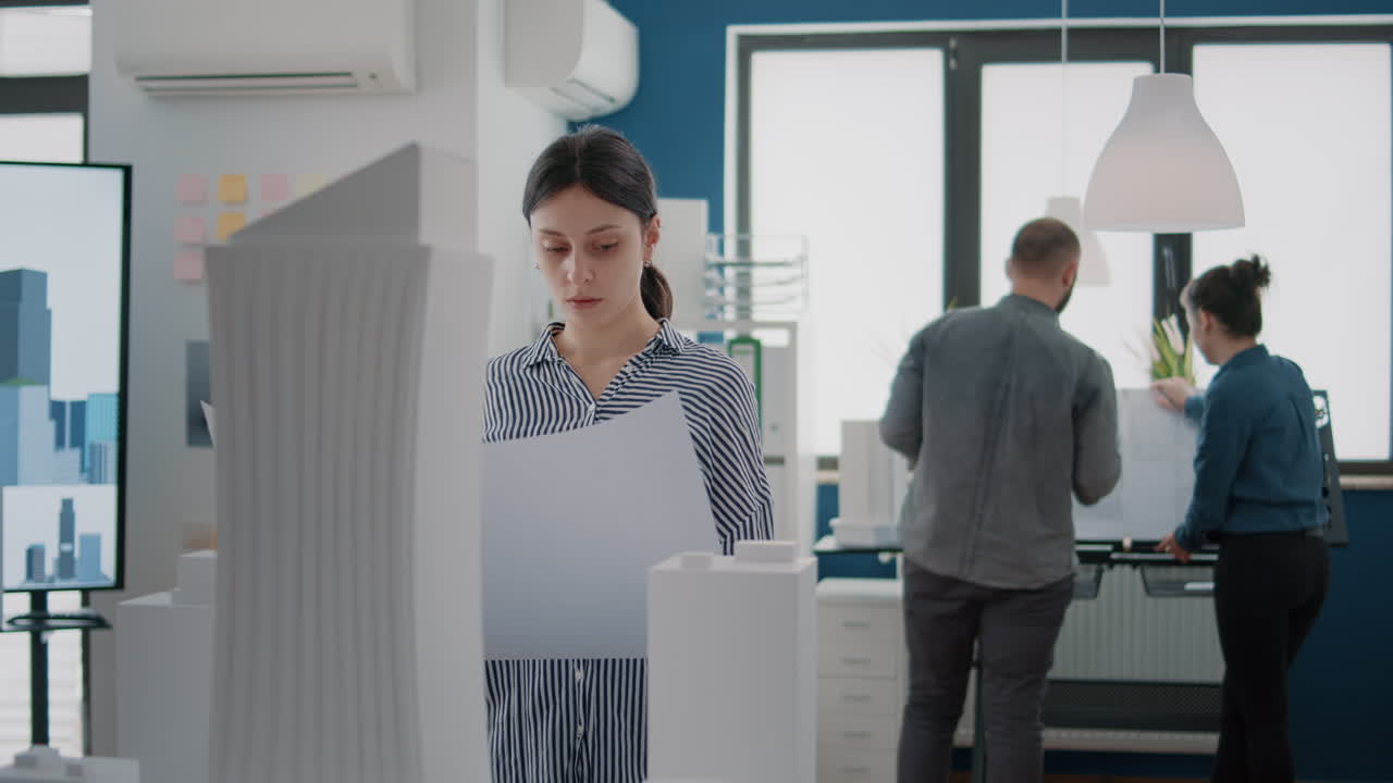 Portrait of woman architect studying blueprints plans on paper to design building model