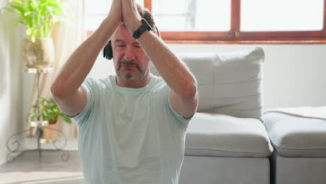 senior man meditating with headphones at home, finding inner peace
