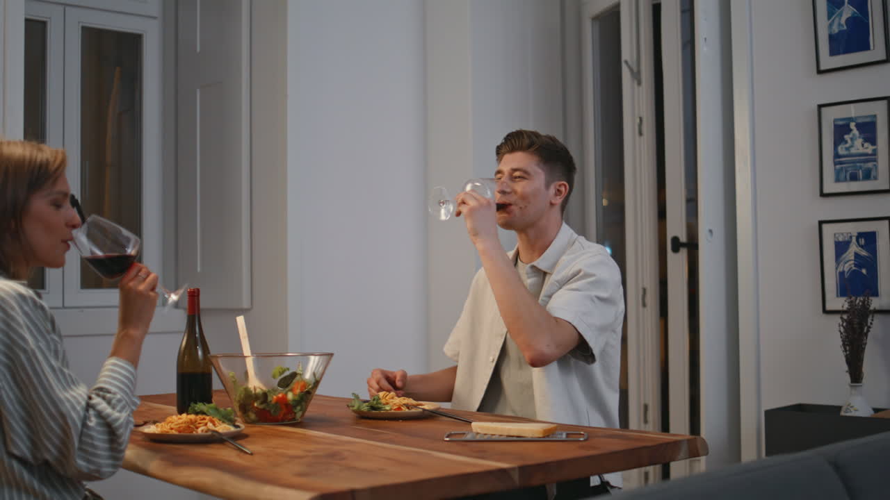 Cheerful family drinking wine in cozy dining room. Happy couple enjoying date