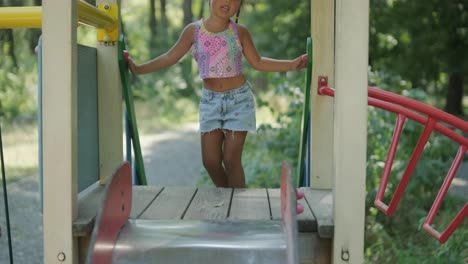 pregnant mother watching daughter play on slide at playground