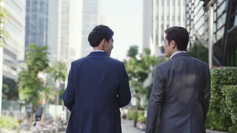 asian business people walking talking on city street
