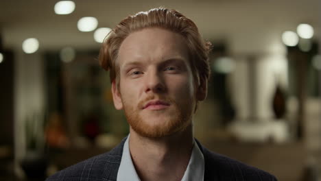 confident business man looking camera in office. redhead man posing camera