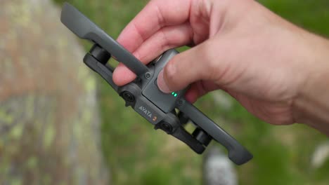 closeup detail of finger turning on dji avata drone, led flashing power