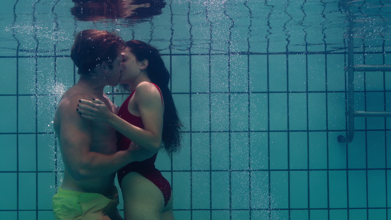 pareja romántica besándose bajo el agua en la piscina jóvenes enamorados disfrutando de un beso íntimo amantes sumergidos en el agua flotando con burbujas en una intimidad apasionada