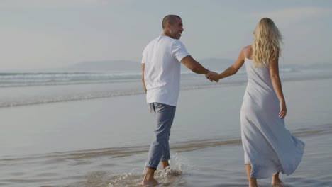 una joven pareja romántica disfrutando de unas vacaciones, caminando por la orilla del mar.