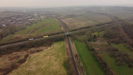 Drohnenaufnahmen,-Die-Autos-Und-Lastwagen-Zeigen,-Die-Auf-Der-Zweispurigen-A2-In-Canterbury-Vorbeifahren,-Während-Sie-über-Hambrook-Sümpfe-Und-Eine-Bahnstrecke-Führt