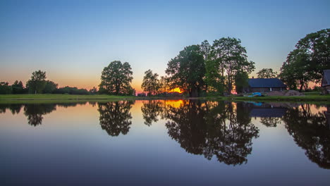 time lapse of a sunset at lake with wooden house and symmetrical reflection