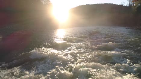spectacular golden lighting on slow motion river rapids in low flying aerial