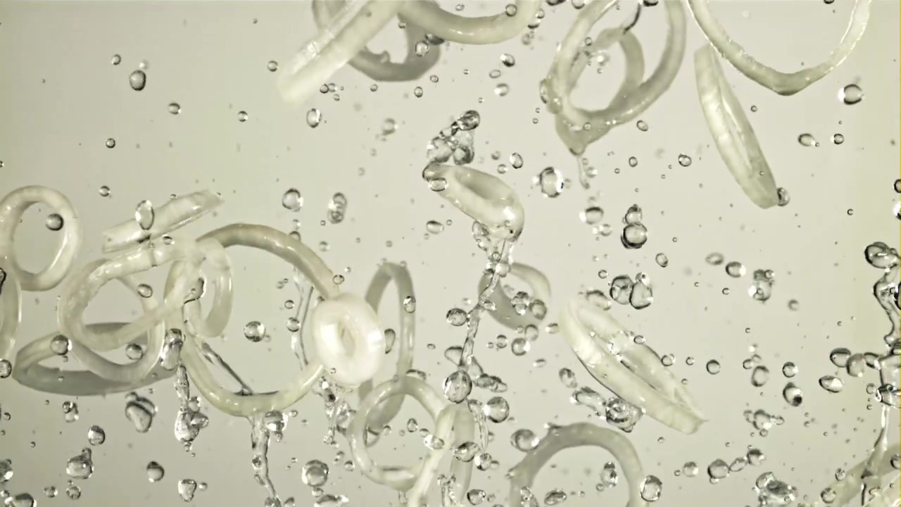 スローモーションで水に飛び散る新鮮なオニオンリング