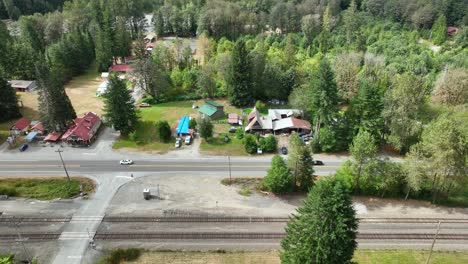 Wide-aerial-view-showcasing-how-train-tracks-run-parallel-to-the-local-highway-of-Baring,-Washington